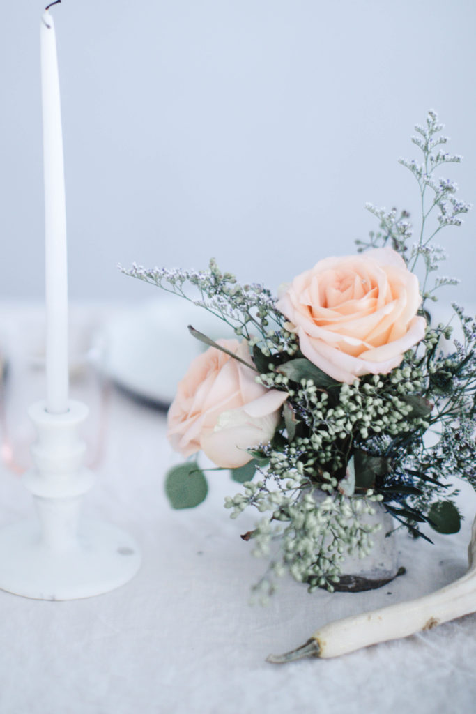 A romantic, rustic, pastel take on the traditional thanksgiving table setting with mismatched plates and linens and peach roses for a soft, casual centerpiece and white candles for decor | photos and styling by Beth Kirby of Local Milk