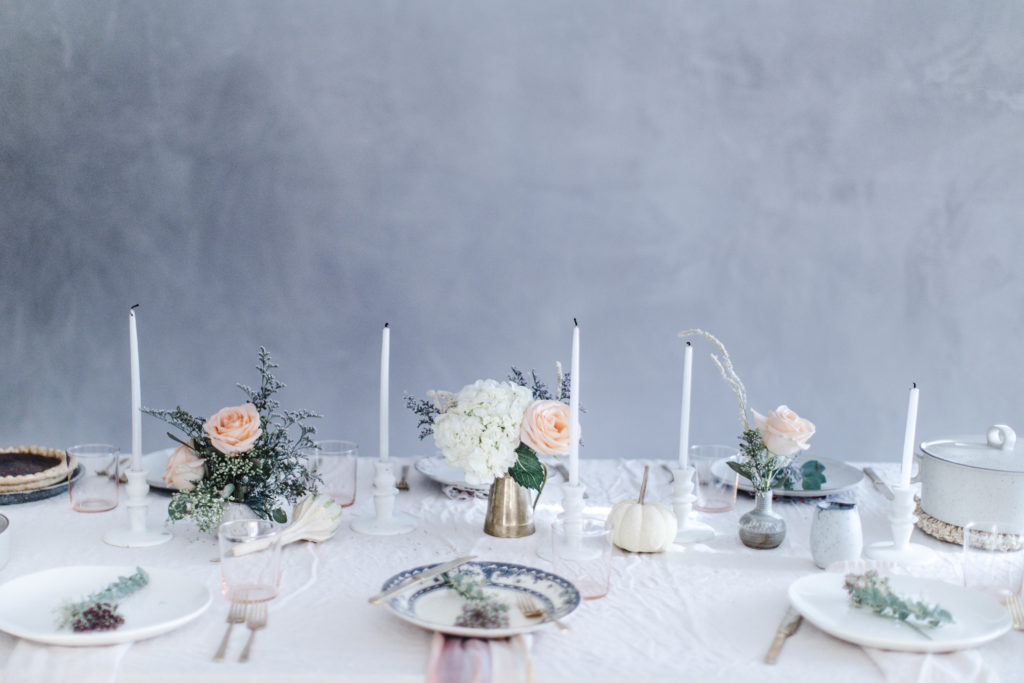 A romantic, rustic, pastel take on the traditional thanksgiving table setting with mismatched plates and linens and peach roses for a soft, casual centerpiece and white candles for decor | photos and styling by Beth Kirby of Local Milk